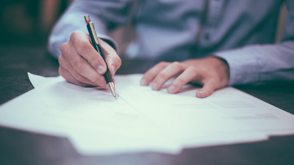 Hand signing tax compliance documents — Brazil Tax Reform Phase 2
